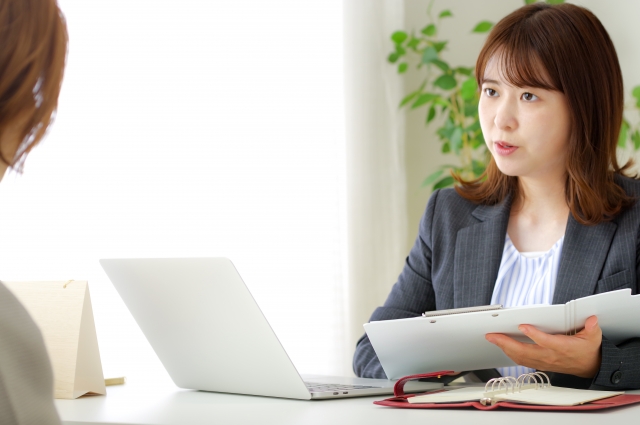 資料を持って説明する女性スタッフのイメージ