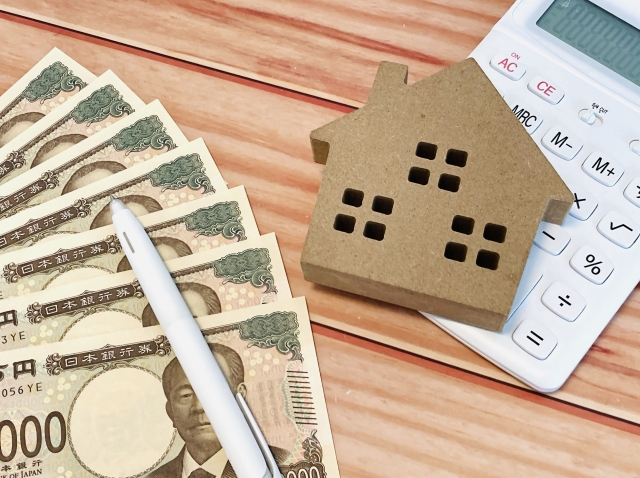 現金と住宅模型・電卓による資金計画のイメージ